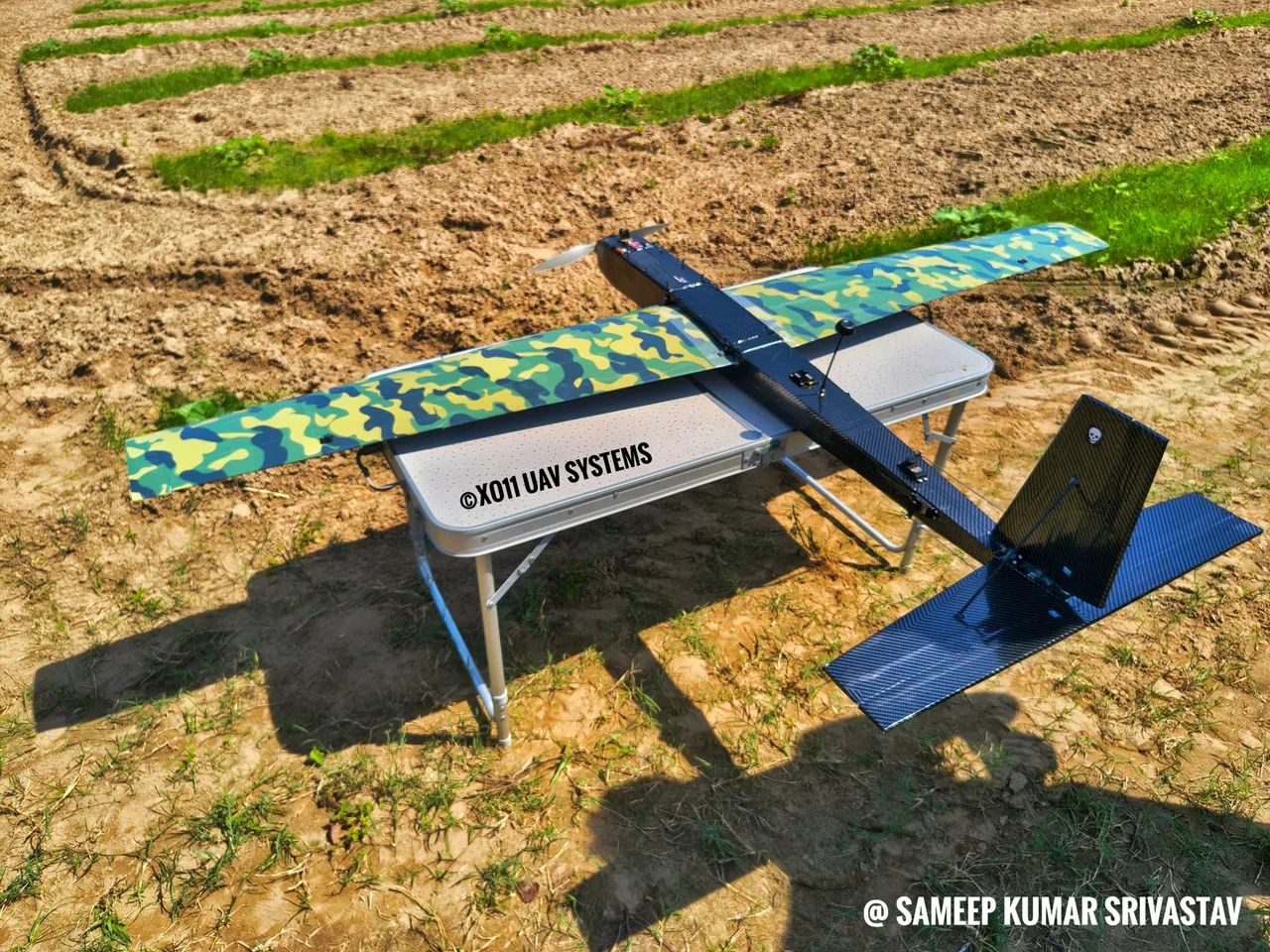 The XO11 2200 mm UAV on a folding table in a field, marked © XO11 UAV Systems